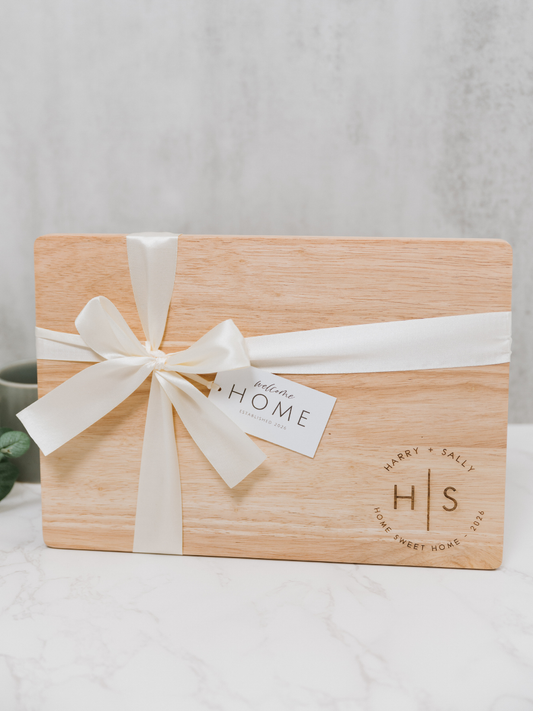 Wooden cutting board with a white ribbon and 'Home' tag on a light background
